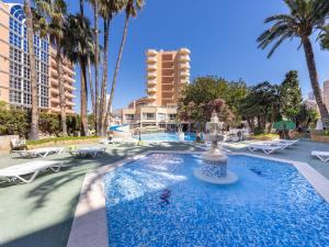 a fountain in the middle of a pool with palm trees at Hotel Alone in Cala de Finestrat