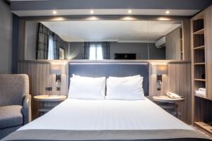 a bedroom with a bed and a chair and a mirror at Holiday Inn Glasgow City Theatreland by IHG in Glasgow +55 photos