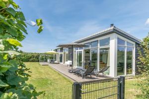 a house with a conservatory with chairs and an umbrella at Buitenplaats Oudendijke in Ellemeet