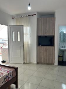 a living room with a bed and a tv and a door at Grandma's in Sarandë
