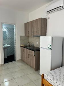 a kitchen with wooden cabinets and a white refrigerator at Grandma's in Sarandë +17 photos