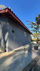 a white building with a red roof and some plants at Chalé com lareira externa e vista para o Pico do Lopo in Extrema