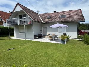 a white house with a table and an umbrella at InNatura Velden in Velden am Wörthersee