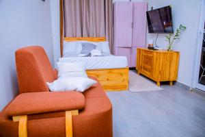 a bedroom with a bed and a chair and a television at ExtraMile Apartments - Cozy Studio in Dodoma