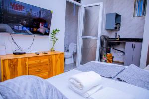 a bedroom with a bed and a toilet and a tv at ExtraMile Apartments - Cozy Studio in Dodoma