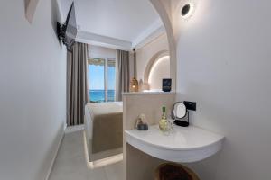ein Badezimmer mit Waschbecken, Bett und Spiegel in der Unterkunft néreya luxury rooms in Charaki