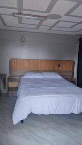 a bedroom with a large bed with a wooden headboard at Rimayalounge in Embu