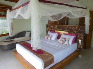 sypialnia z łóżkiem z baldachimem i kanapą w obiekcie Puri Dajuma Villas w mieście Pulukan