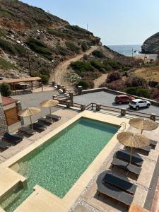 a swimming pool with chairs and umbrellas next to the ocean at Alia Andros in Vitálion