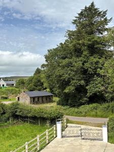 a barn in a field with a fence and a tree at Castleroddy House - spacious country house - king beds - extensive parking in Lislap