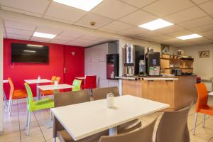 a restaurant with a white table and chairs and red walls at Premiere Classe Liege / Luik in Liège