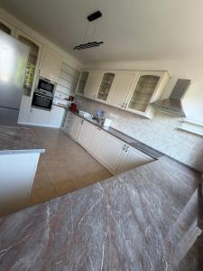 a kitchen with white cabinets and a tile floor at Ide Vissza apartman 3 in Siófok