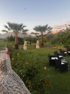 a garden with tables and chairs and palm trees at Villa Ursino in Scalea