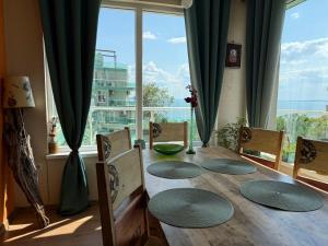 a dining room table with chairs and a large window at Europe Holiday Apartments First Sea Line Coast in Pomorie