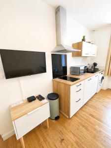 a kitchen with white cabinets and a flat screen tv at Le Byzantin - T2 Hyper centre in Pontivy