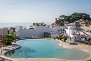 a large swimming pool in front of a white building at Hotel Delfín 4 Sup in Tossa de Mar