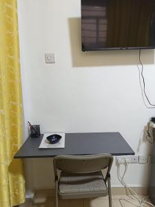 a desk with a chair and a television on a wall at Gweth Haven Homes in Nakuru