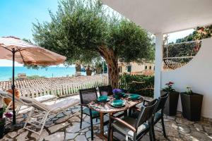 a patio with a table and chairs and a tree at Corfu Dream Holidays Villas in Glyfada