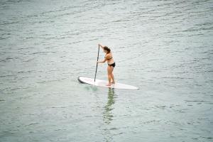 a woman in a bikini on a paddle board in the water at Cookies Salad Resort in Salad Beach