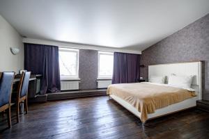 a bedroom with a bed and a desk and two windows at G40 Boutique Hotel in Odesa