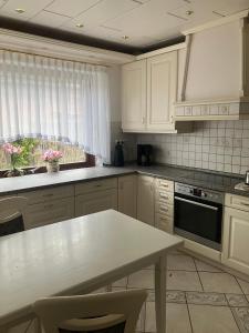 a kitchen with white cabinets and a table and a window at Haus Eichholz in Tellingstedt