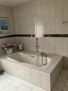 a large bath tub in a bathroom with a tile wall at Haus Eichholz in Tellingstedt +7 photos
