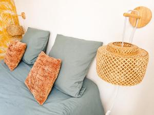 a couch with two pillows and a rattan basket at Le Byzantin - T2 Hyper centre in Pontivy