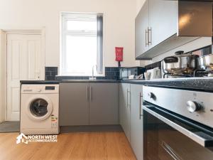 a kitchen with a washer and dryer in it at Leigh 2-Bedroom House Near Haydock & Wigan in Leigh +20 photos