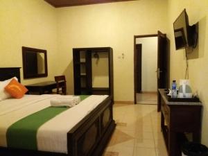 a bedroom with a bed and a dresser in it at Alam Jogja Resort Mitra RedDoorz in Yogyakarta