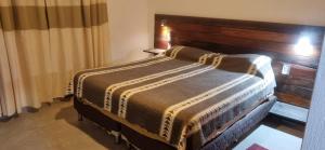 a bedroom with a bed with a wooden headboard at Cata, Casa de Descanso in Salta