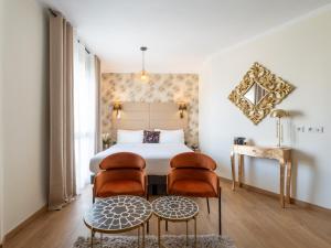 a bedroom with a bed with two chairs and a table at Hôtel La Villa Cannes in Cannes