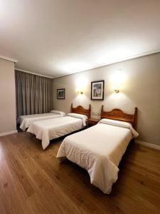 two beds in a hotel room with wood floors at Hotel Salvador in Bailén +22 photos