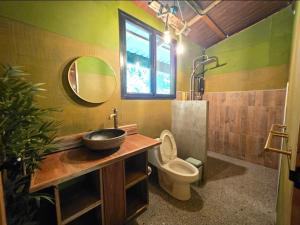 a bathroom with a sink and a toilet and a mirror at Khao Sok Silver Cliff Resort in Khao Sok National Park