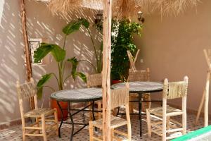 a dining room with two tables and chairs and plants at Riad Chouara in Fez