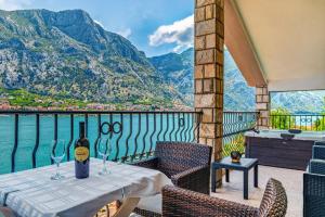 a table with wine glasses on a balcony with mountains at Apartments Vuković in Kotor