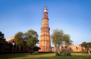 a tall tower in a park next to a building at Grand Tree Hotel Shree Guru in New Delhi