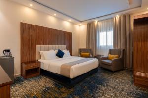 a hotel room with a bed and a chair at القصر الإسكان in Khamis Mushayt