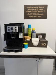 eine Theke mit einer schwarzen Kaffeemaschine und einer Schachtel darauf in der Unterkunft Артур in Berdychiv