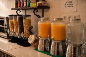 a kitchen counter with two jars of cereal and orange juice at Posada El Valle - Adults Only in Suances