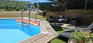a swimming pool with a bench and an umbrella at Gîte 1- LE RAZAL in Vallon-Pont-dʼArc