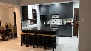 a large kitchen with black cabinets and a table at Tivoli House in Edgemead