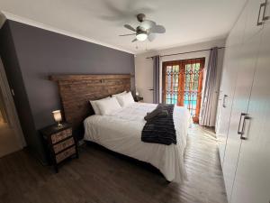 a bedroom with a bed and a ceiling fan at Tivoli House in Edgemead +9 photos