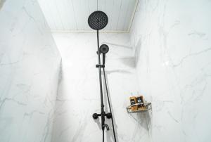 a shower in a bathroom with white marble walls at Pondok Bingin Guest House in Bingin Beach