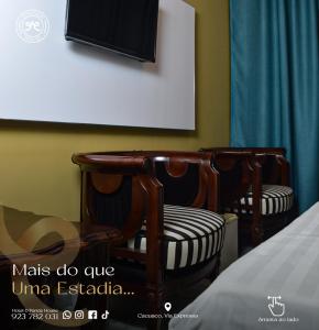 two chairs in a room with a tv on the wall at Hotel DPanda House in Cacuaco
