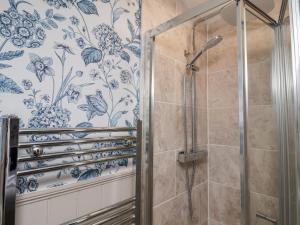 a bathroom with a shower with blue and white wallpaper at Lansdowne Grange in Bridlington +43 photos