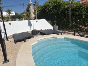 a swimming pool with two chairs and an umbrella at Casa El Flamenco Zoutmeer Torrevieja 6 of 8 personen in Torrevieja