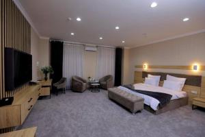 a bedroom with a large bed and a flat screen tv at Valor Hotel in Tashkent