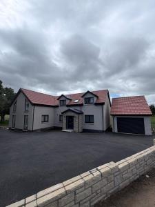 a large white house with red roofs and a driveway at Cour Cottage in Drem