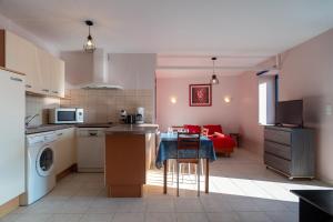 a kitchen and living room with a red couch in the background at Les Chouettes - Au Soleil Breton in Saint-Nic