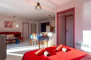 a bedroom with a red bed and a living room at Les Chouettes - Au Soleil Breton in Saint-Nic